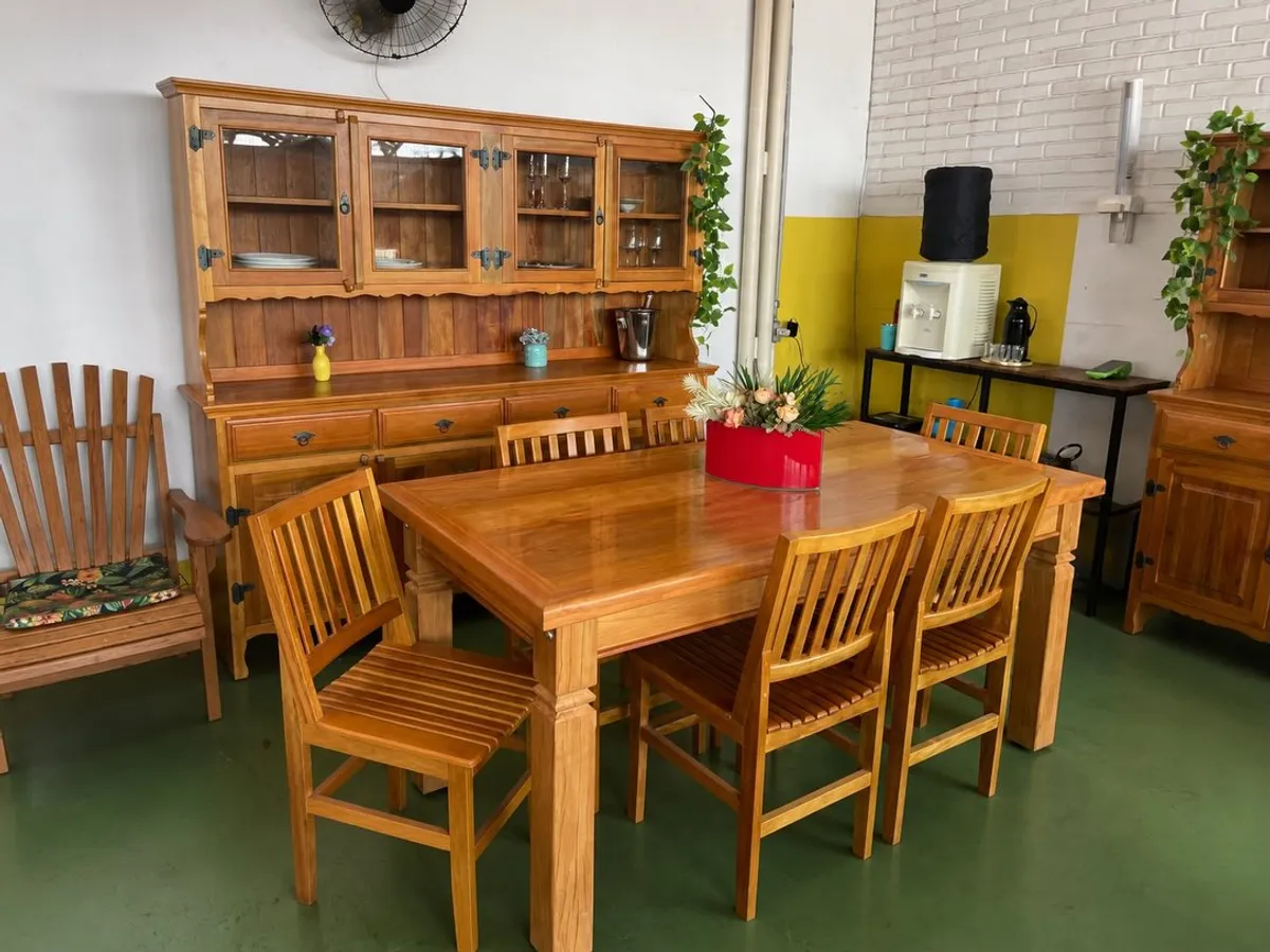 Mesa de jantar retangular com seis cadeiras e cristaleira ao fundo